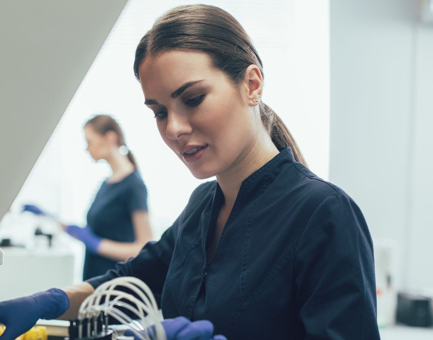 Researcher in a laboratory handling analytical equipment with blue gloves