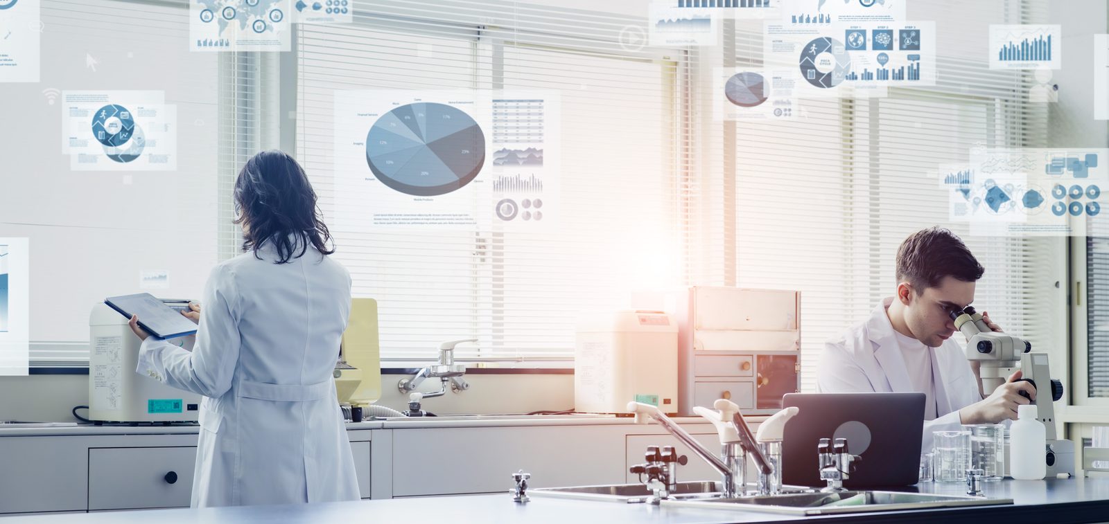 Two scientists working in a modern laboratory with data screens in the background